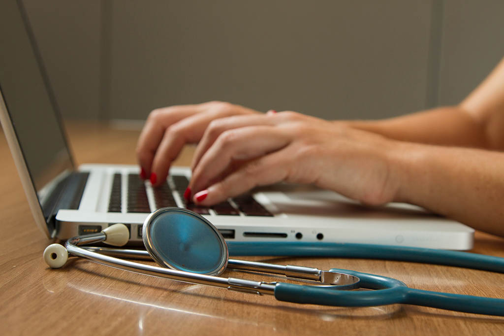 stethoscope and someone working on laptop