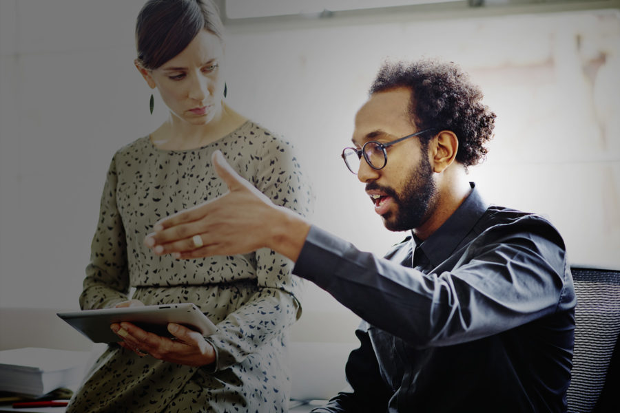 a man talking while a woman takes notes on a tablet