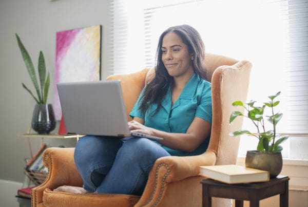 Woman in armchair at home using a laptop