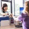 Young woman paying with credit card at doctor's office front desk