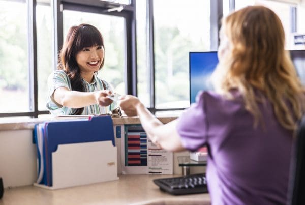 Young woman paying with credit card at doctor's office front desk