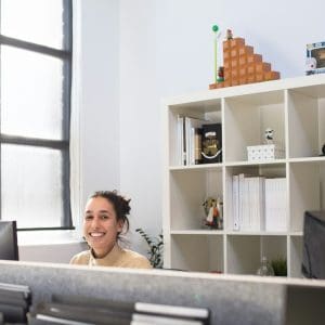 woman working at desk while smiling at camera